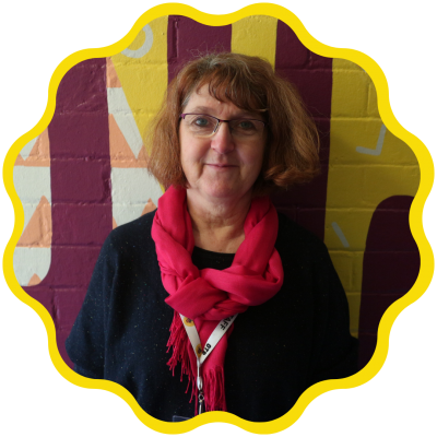 Susan has died red hair and smiles at the camera in a red scarf