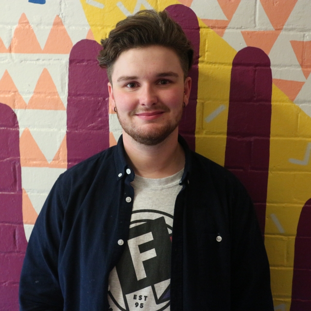 A person wearing freedom logo t-shirt, faces the camera smiling warmly.