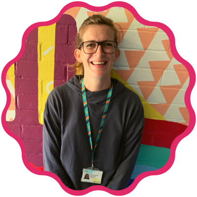 Bronwen is wearing glasses with her hair tied back and a blue sweatshirt. She smiles at the camera